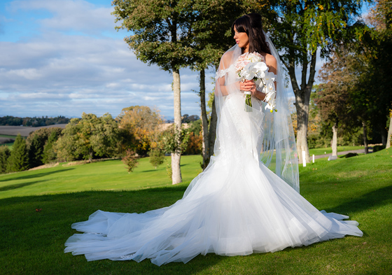 Bride standing outside on grounds holding bouquet